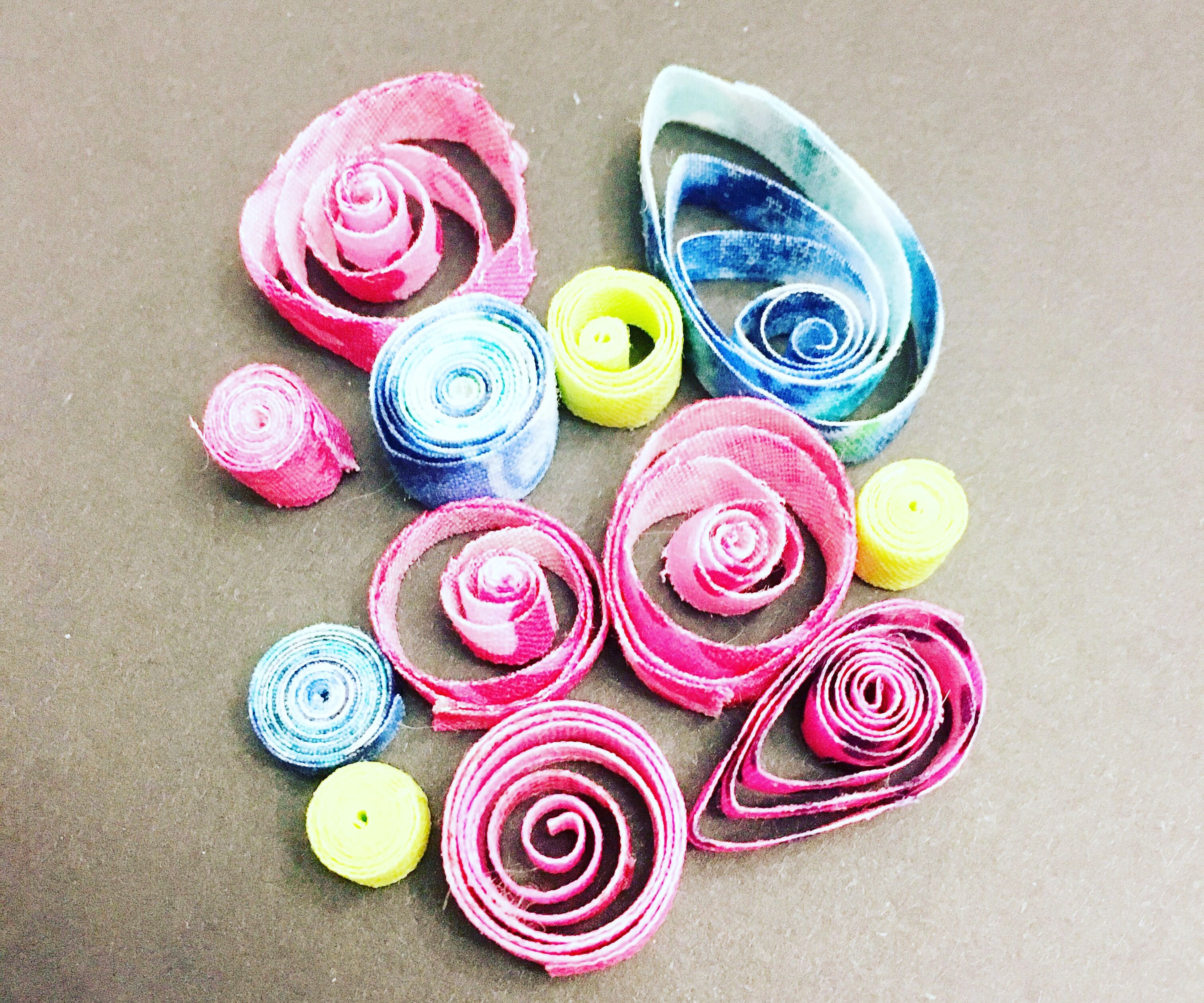 Hands rolling quilling paper into different shapes